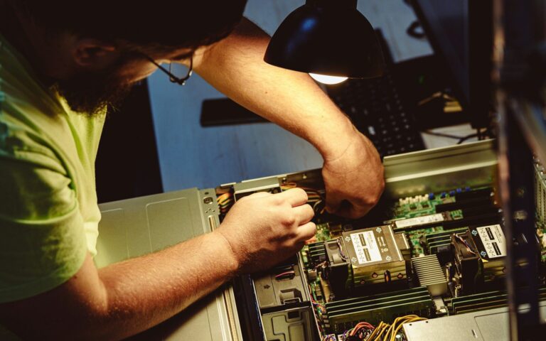 Man repairing a computer server under a lamp.