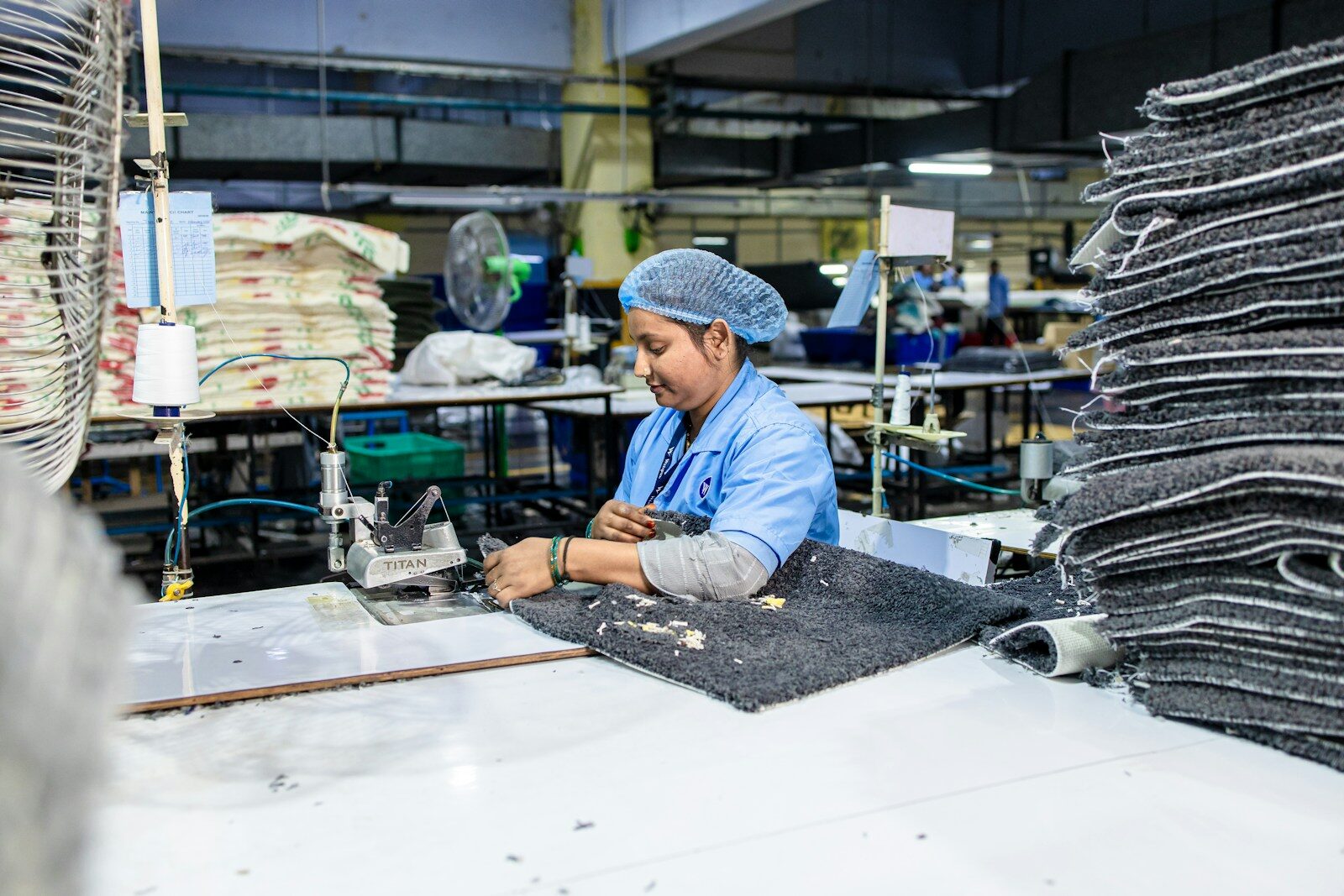 A worker sews at a factory work station.