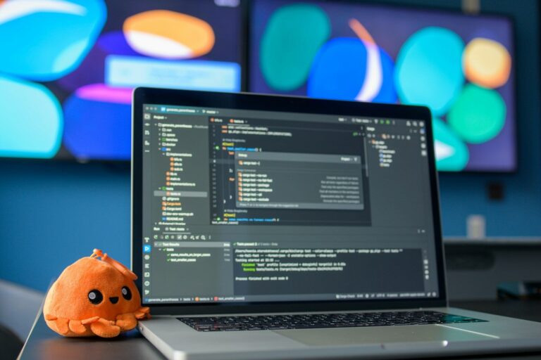 Laptop with code and a small plush octopus.